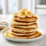 The Ultimate Easy 3 Ingredient Pancakes Recipe for Busy Mornings 3 Easy 3 ingredient pancakes stacked on a plate with banana slices